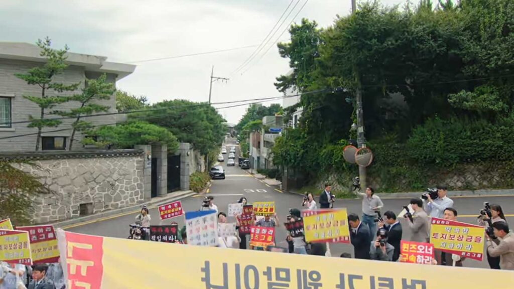 A scene from 'Queen of tears Ep 9' where people protesting for land compensation